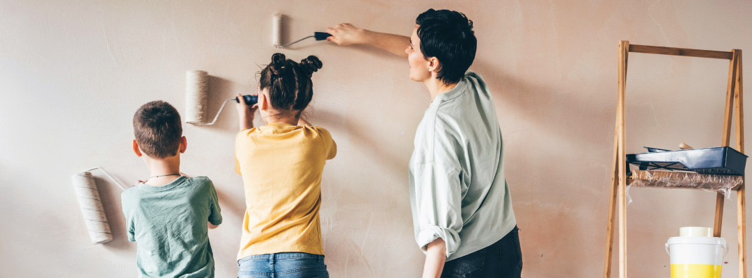 Women and her kids painting a wall.